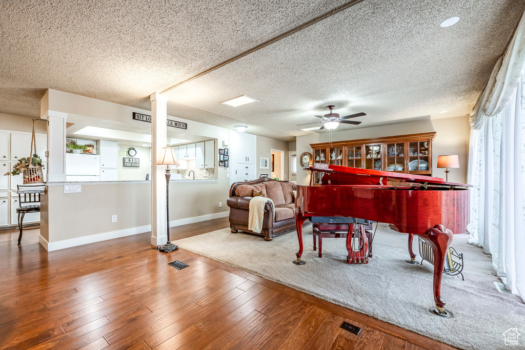 Living area featuring baseboards, a textured ceiling, ceiling fan, and hardwood / wood-style flooring