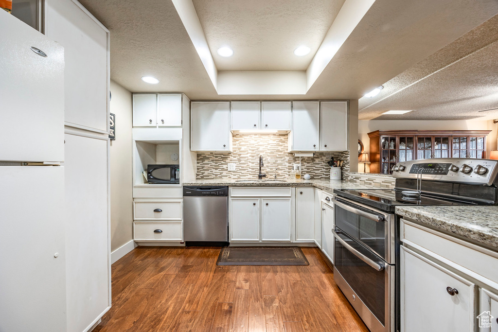 Kitchen featuring a sink, stainless steel appliances, dark wood-style floors, and a textured ceiling