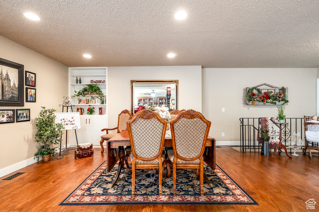 Dining area with recessed lighting, a textured ceiling, and wood finished floors