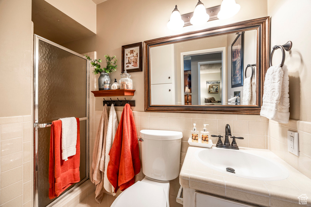 Full bathroom featuring vanity, tile walls, a stall shower, and toilet