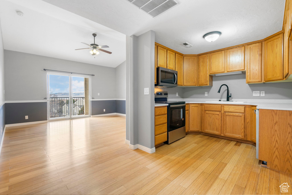 Kitchen featuring appliances with stainless steel finishes, light hardwood / wood-style flooring, ceiling fan, and sink