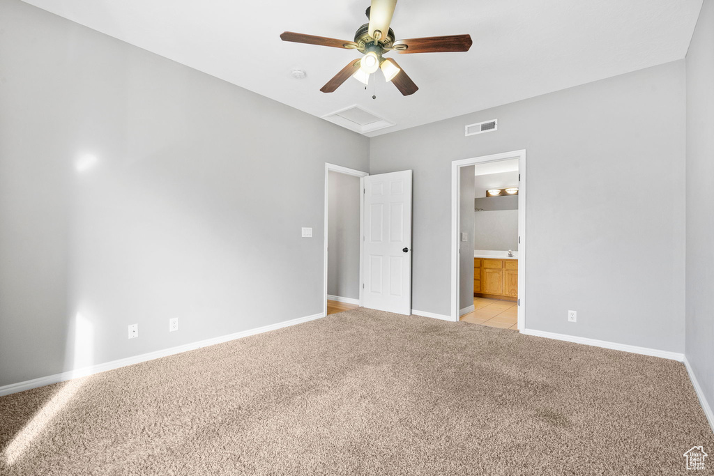 Unfurnished bedroom with ceiling fan, ensuite bathroom, and light colored carpet