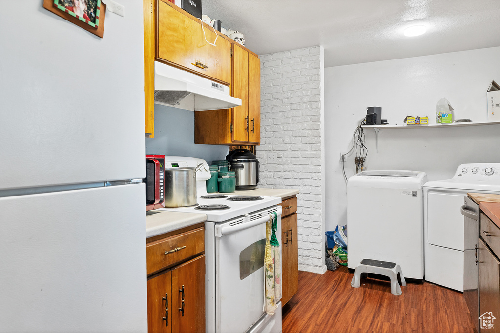 Kitchen featuring independent washer and dryer, white appliances, and dark wood-type flooring