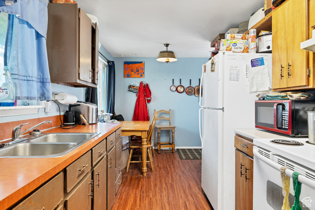 Kitchen with electric range, dark hardwood / wood-style floors, sink, and hanging light fixtures