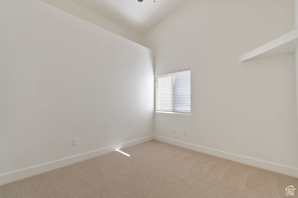 Spare room with high vaulted ceiling and light colored carpet