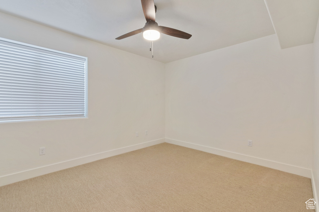 Carpeted spare room featuring ceiling fan