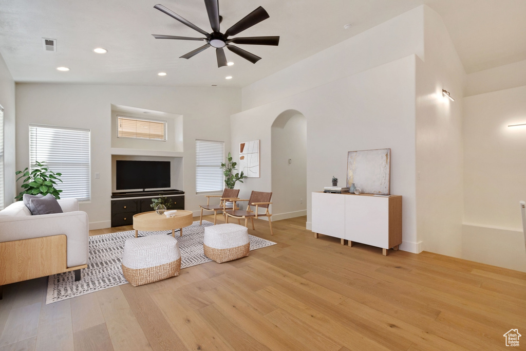 Living room with ceiling fan, high vaulted ceiling, and light hardwood / wood-style floors