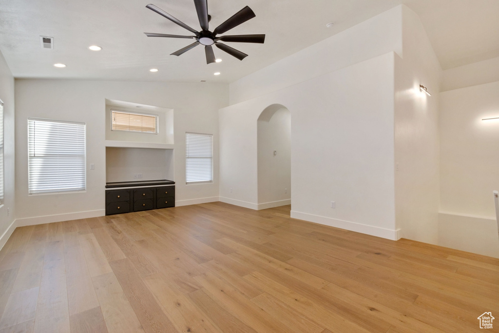 Unfurnished living room with light wood-type flooring, vaulted ceiling, and ceiling fan