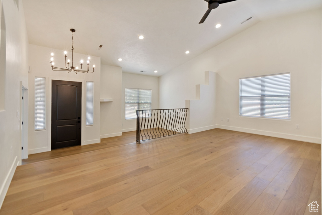 Entryway with ceiling fan with notable chandelier, light hardwood / wood-style floors, and high vaulted ceiling