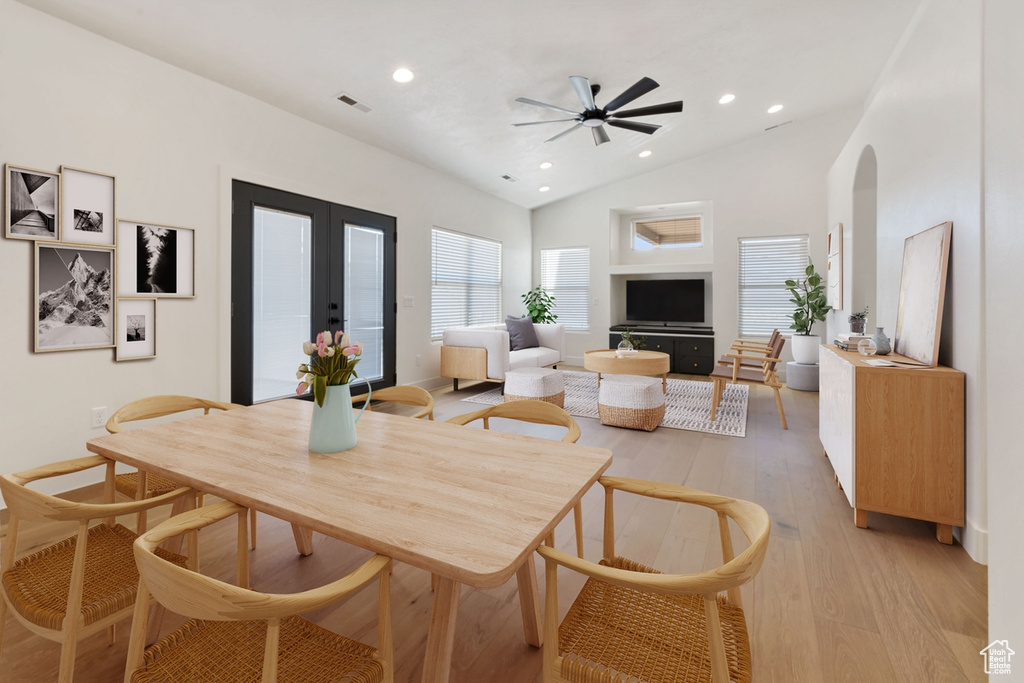 Dining area with ceiling fan, light hardwood / wood-style floors, high vaulted ceiling, and french doors