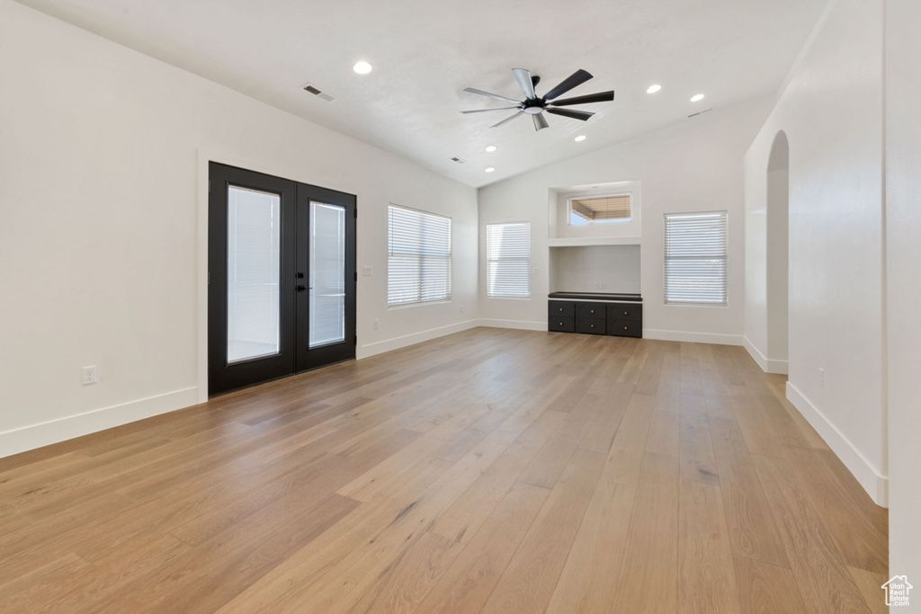 Unfurnished living room featuring ceiling fan, lofted ceiling, light hardwood / wood-style flooring, and french doors