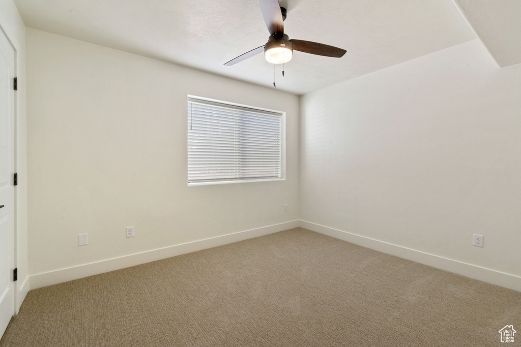 Carpeted spare room featuring ceiling fan