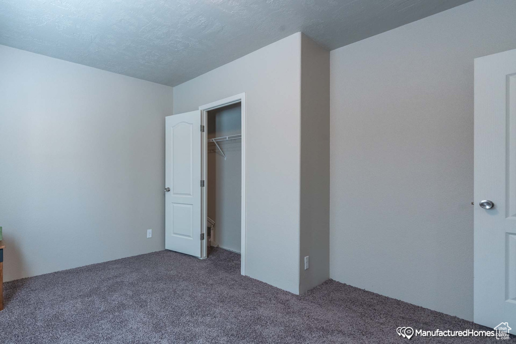 Unfurnished bedroom featuring carpet flooring, a closet, and a textured ceiling