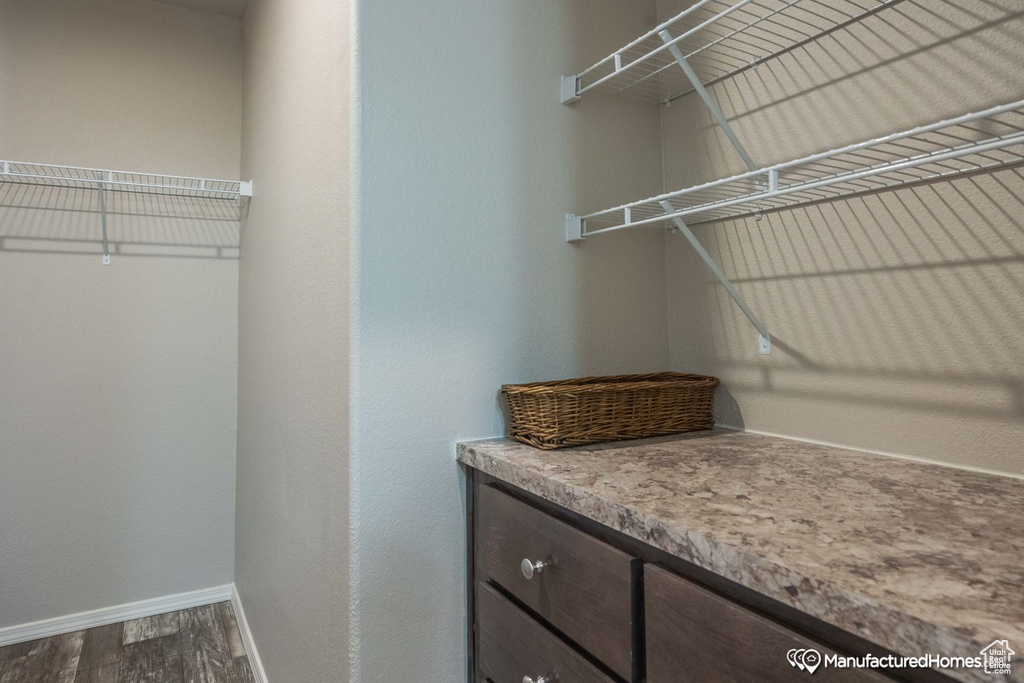 Walk in closet with hardwood / wood-style floors