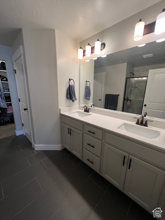 Bathroom with vanity, a textured ceiling, tile patterned floors, and an enclosed shower