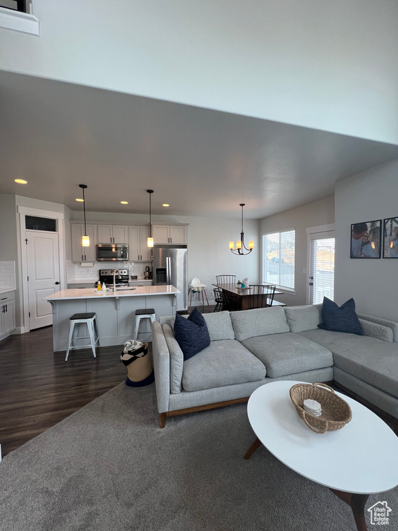 Living room with a notable chandelier, dark hardwood / wood-style floors, and sink