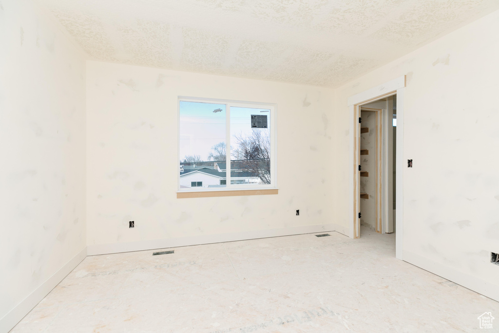 Spare room with visible vents, a textured ceiling, and baseboards