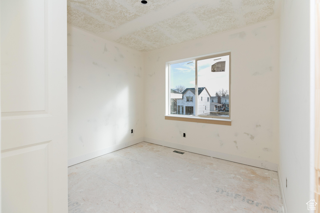 Spare room with a textured ceiling, visible vents, and baseboards