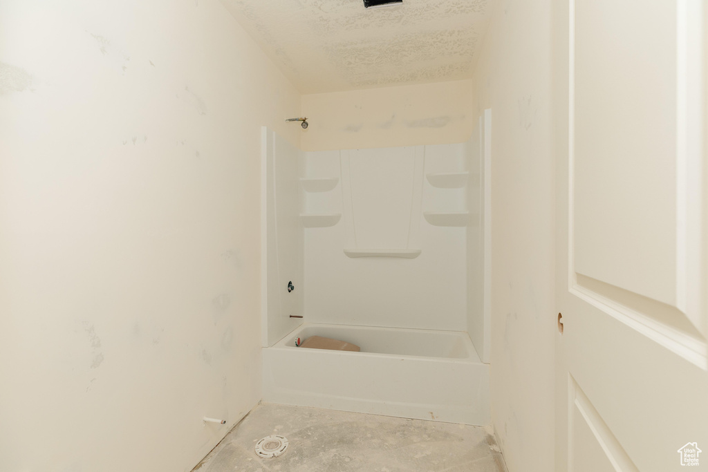 Full bath featuring a textured ceiling and unfinished concrete floors