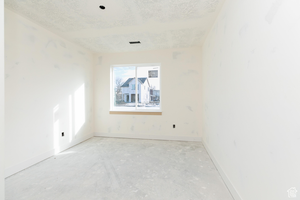 Empty room with a textured ceiling and baseboards