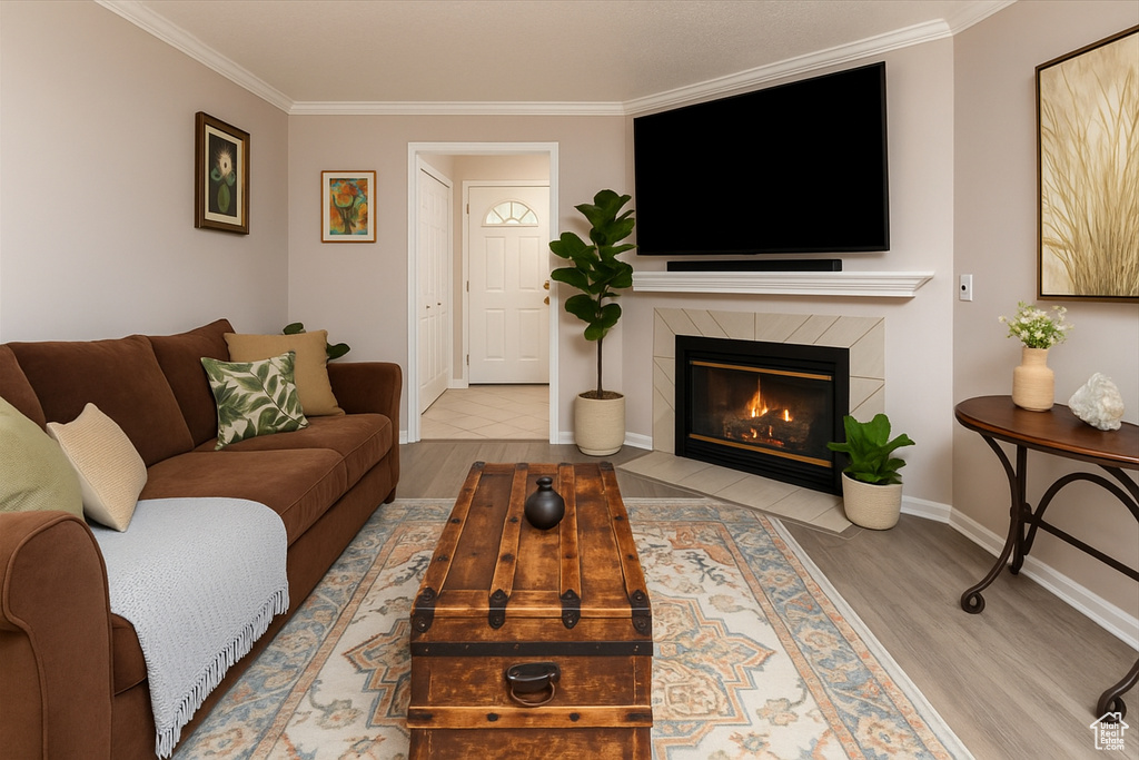 Living room with crown molding, wood finished floors, a tile fireplace, and baseboards