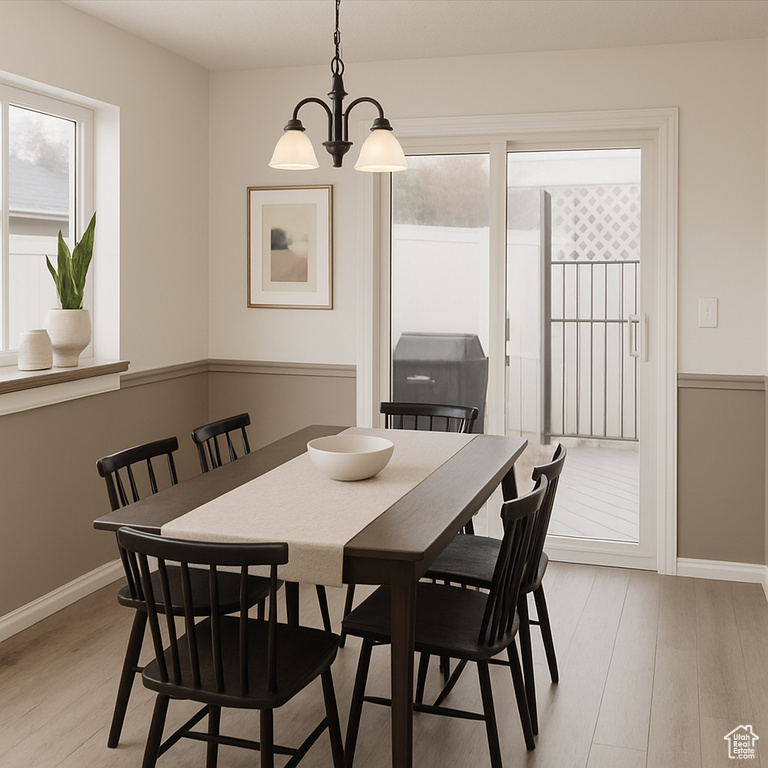 Dining room with light wood finished floors, a chandelier, and baseboards