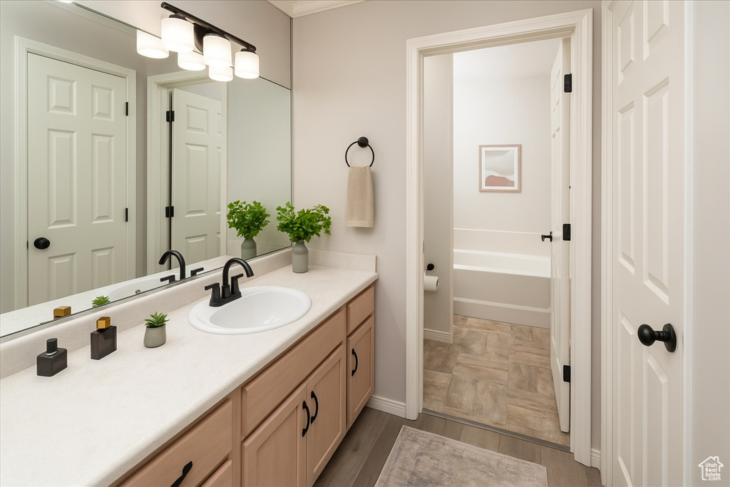 Full bathroom featuring vanity, baseboards, and a bath