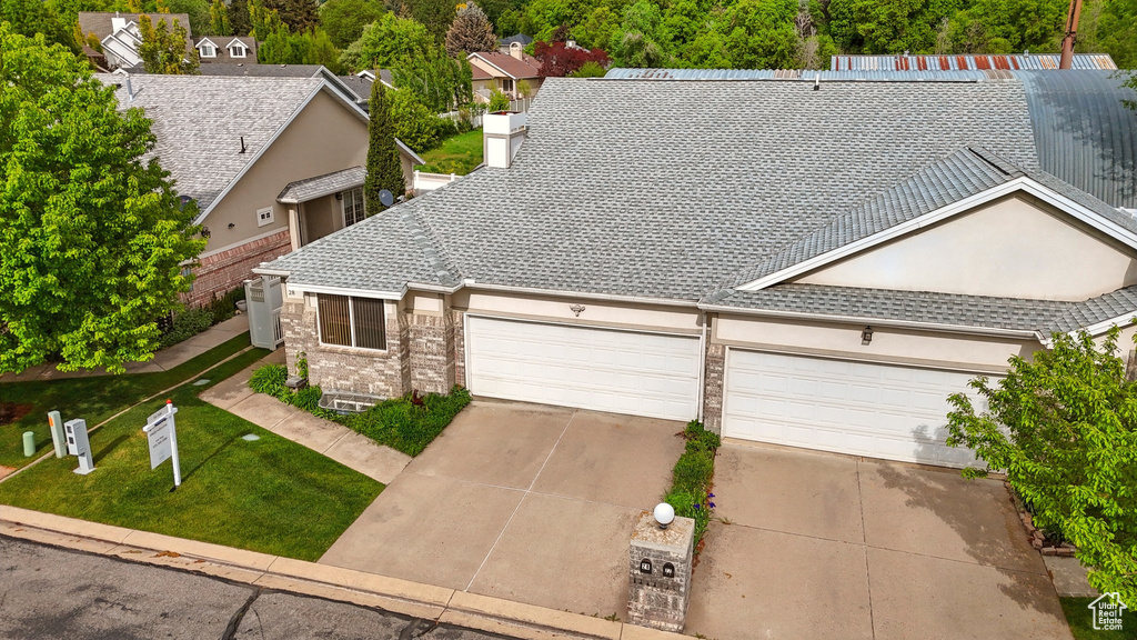 Traditional-style house with driveway, a garage, a front yard, brick siding, and a shingled roof