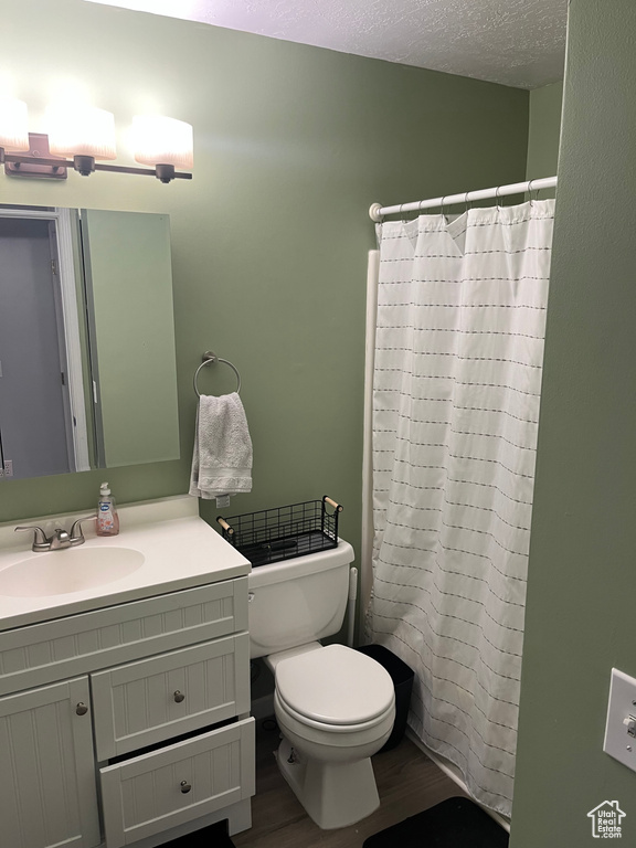 Bathroom with toilet, wood-type flooring, walk in shower, a textured ceiling, and vanity