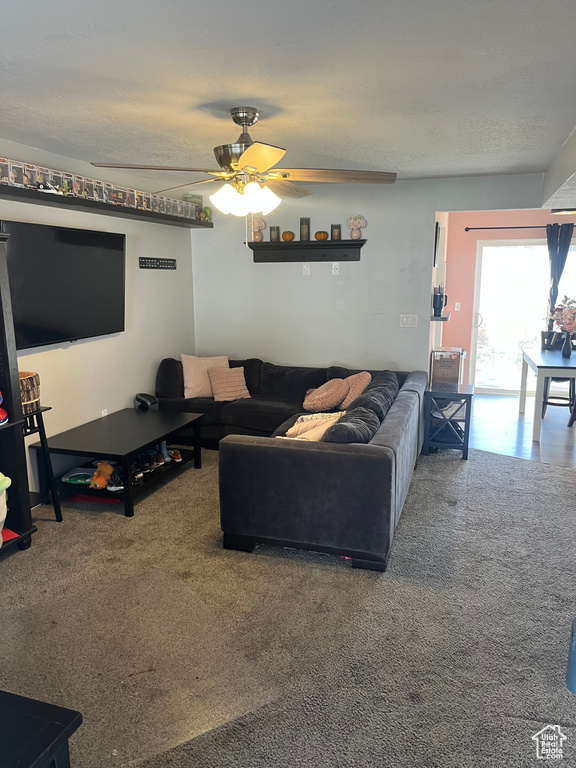 Carpeted living room featuring a textured ceiling and ceiling fan