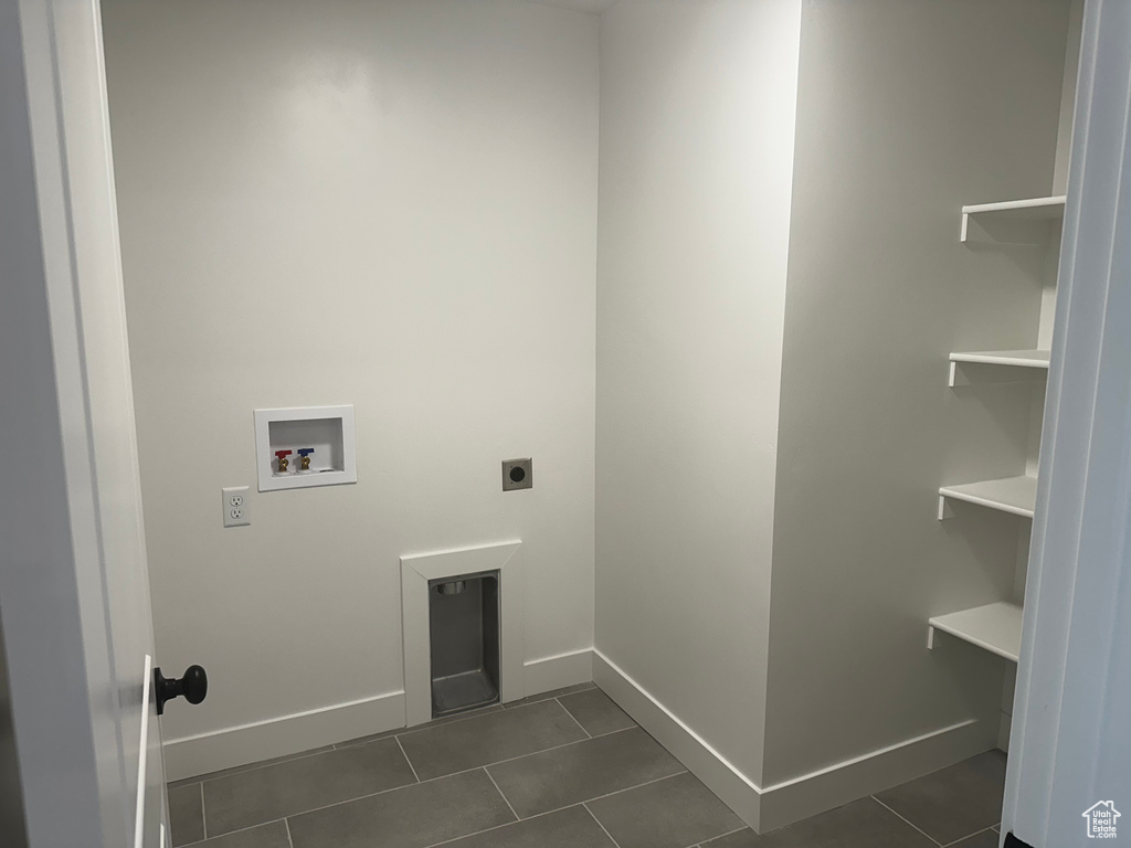 Washroom featuring hookup for an electric dryer, hookup for a washing machine, and dark tile patterned flooring