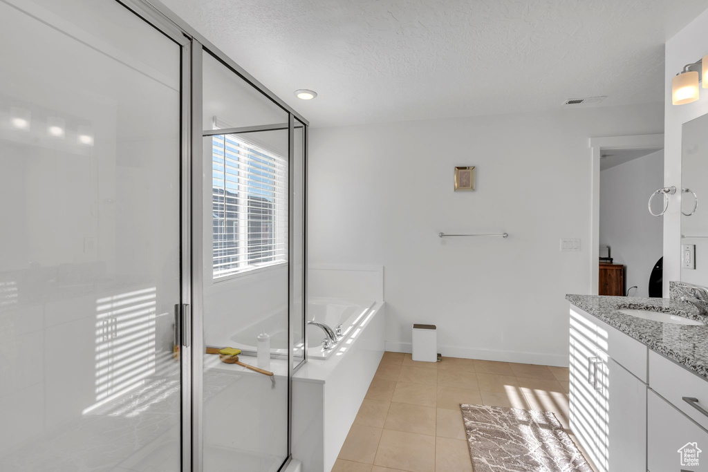 Bathroom with tile patterned floors, vanity, plus walk in shower, and a textured ceiling
