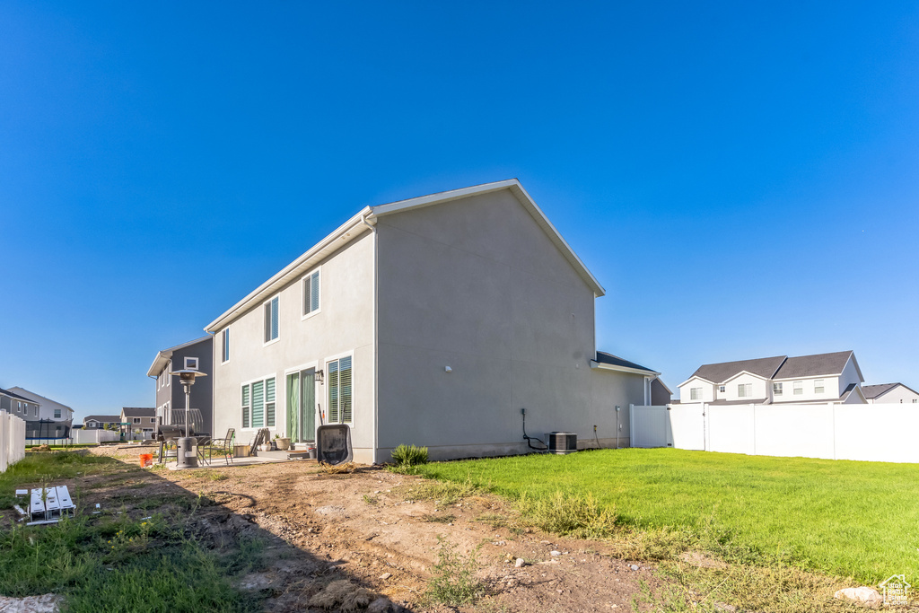 Back of property with a patio area, a yard, and central AC unit