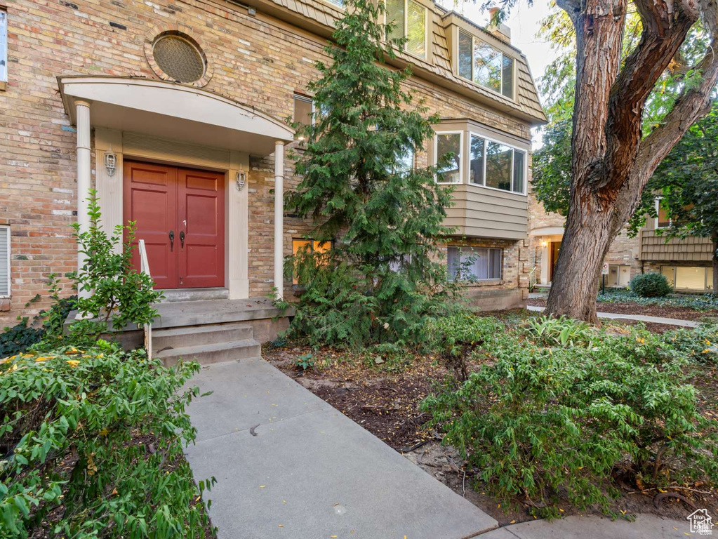 Entrance to property featuring brick siding and mansard roof
