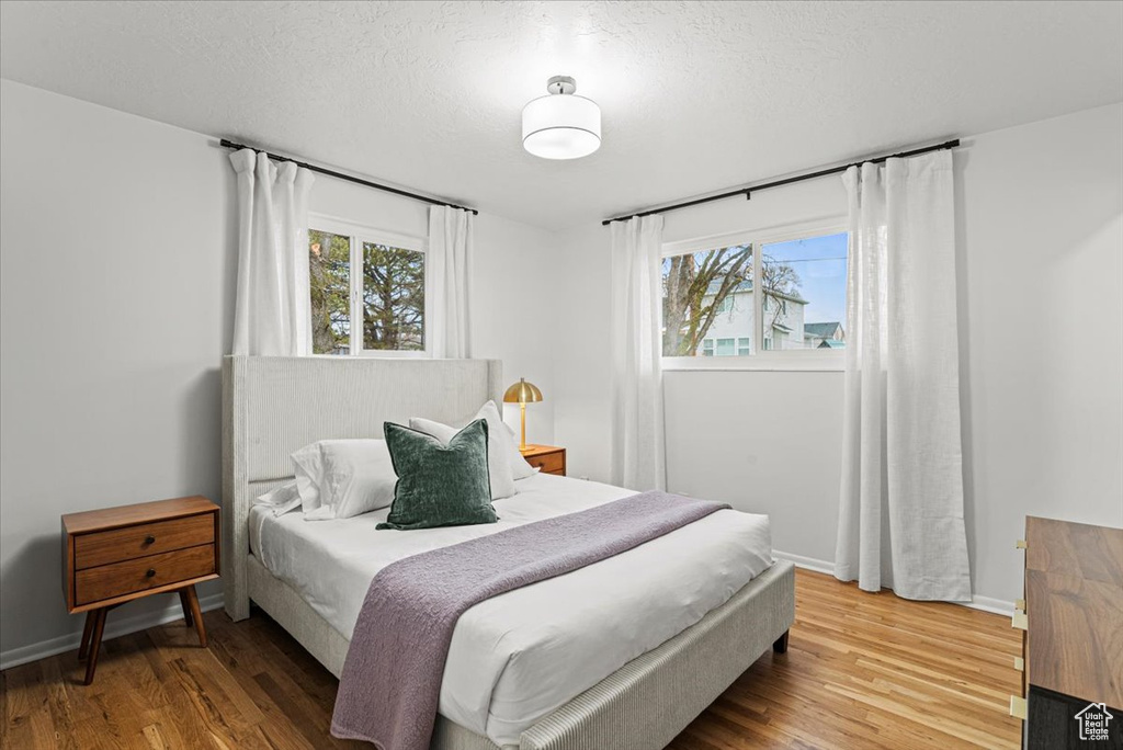 Bedroom with hardwood / wood-style floors, a textured ceiling, and multiple windows