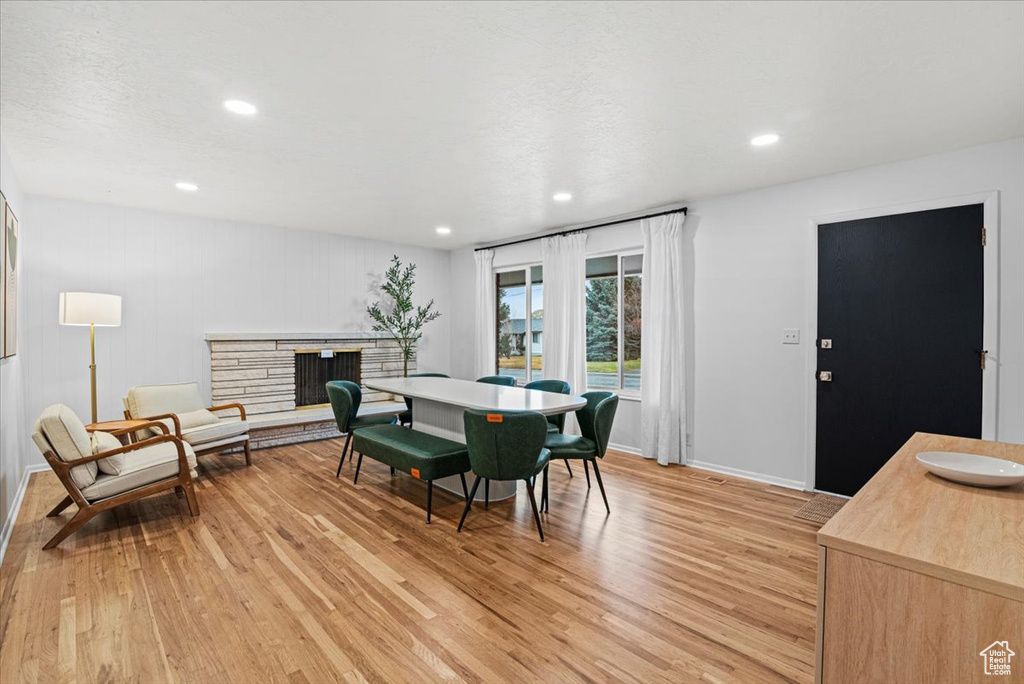 Dining area with a stone fireplace and light wood-type flooring
