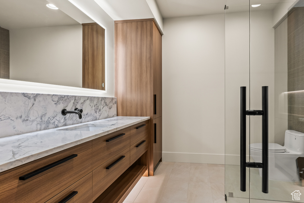 Bathroom featuring backsplash, tile patterned floors, vanity, and toilet