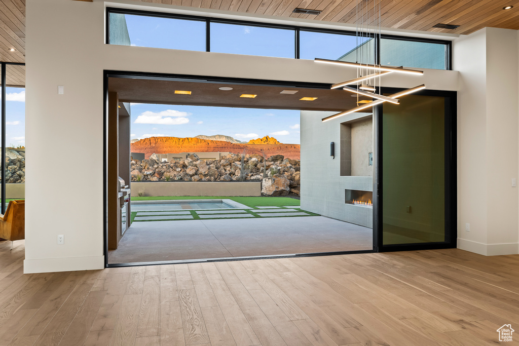 Doorway to outside featuring a high ceiling, a mountain view, a fireplace, wood ceiling, and light wood-type flooring