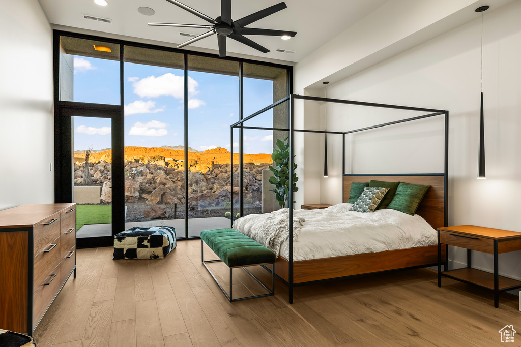 Bedroom with floor to ceiling windows, a mountain view, ceiling fan, and light wood-type flooring