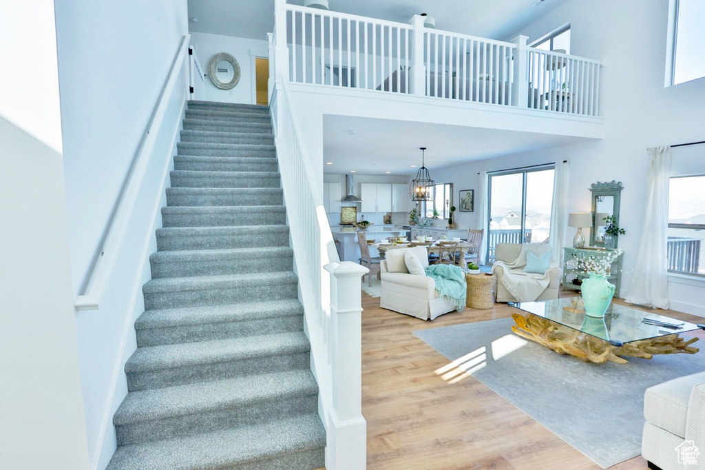 Staircase with hardwood / wood-style flooring and a towering ceiling