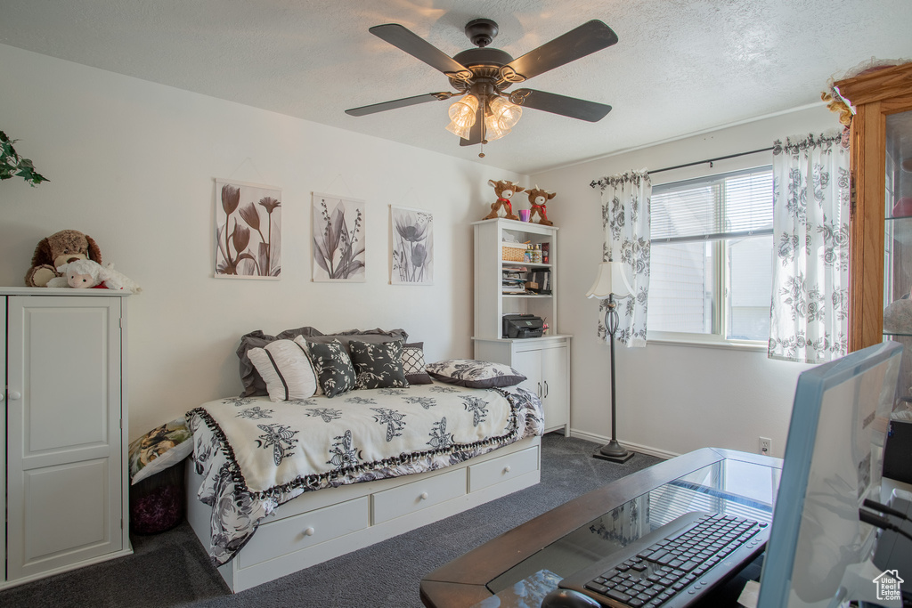 Carpeted bedroom featuring ceiling fan and a textured ceiling