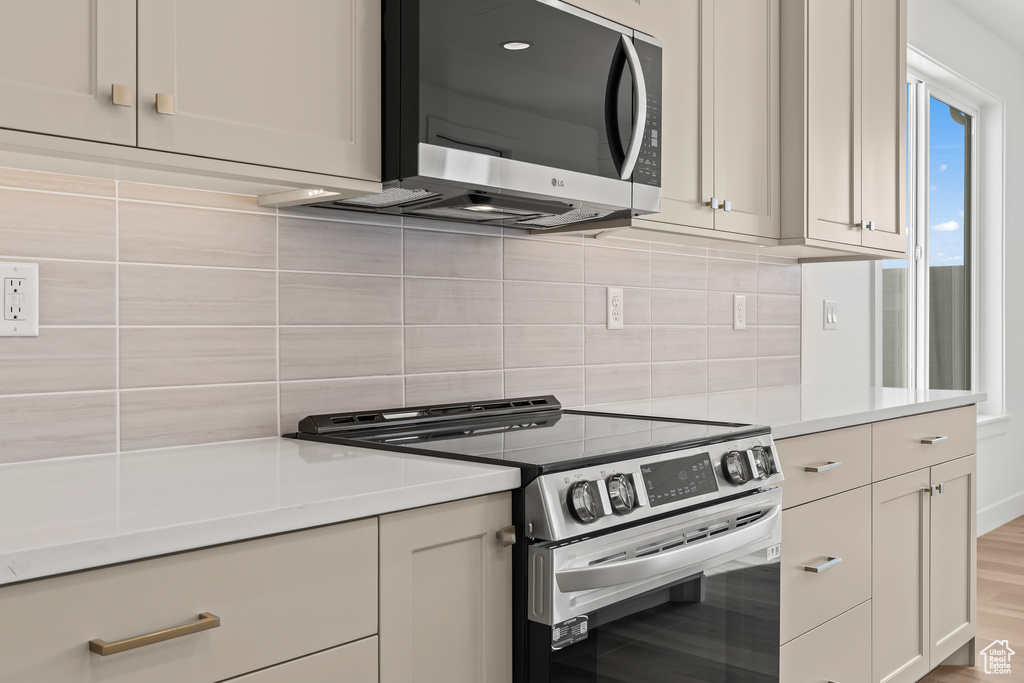 Kitchen with white cabinetry, light wood-type flooring, stainless steel appliances, and tasteful backsplash