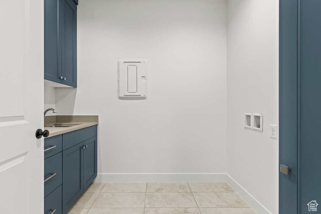 Laundry area featuring washer hookup, light tile patterned flooring, cabinets, and sink