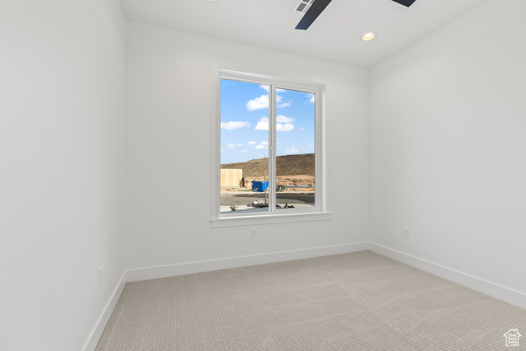 Empty room featuring light colored carpet and ceiling fan