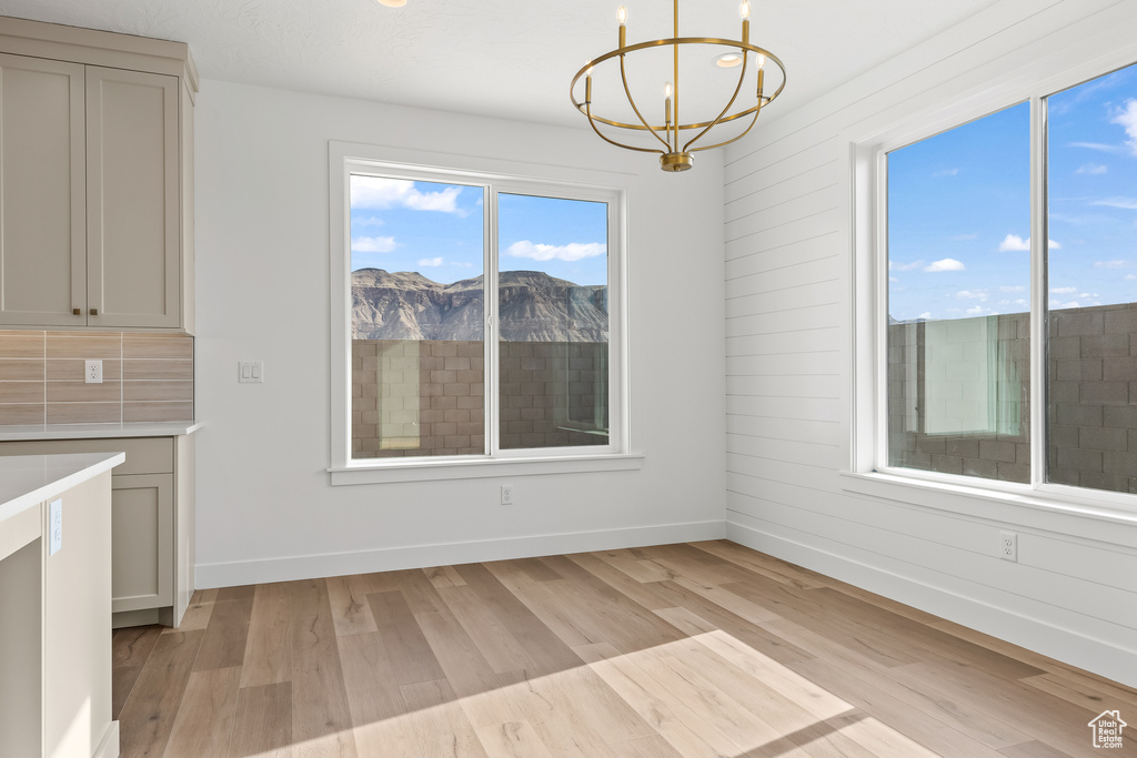 Unfurnished dining area featuring a notable chandelier, a mountain view, and light hardwood / wood-style floors