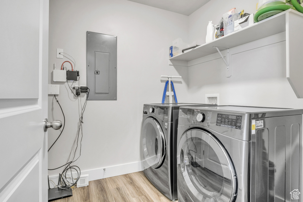 Washroom with washer and dryer, electric panel, and light hardwood / wood-style flooring