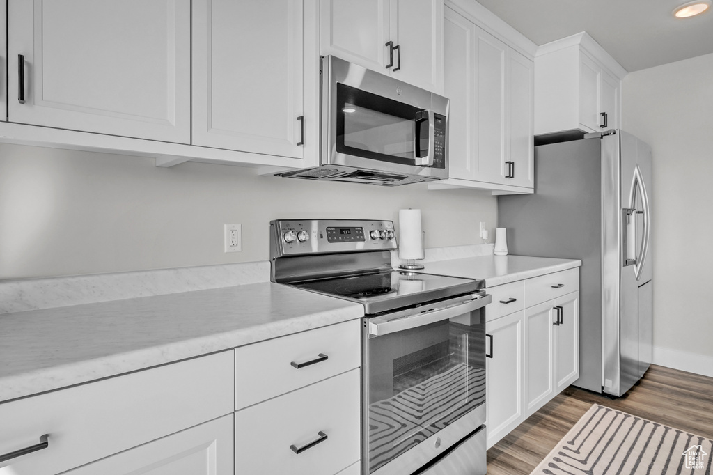 Kitchen with white cabinetry, light hardwood / wood-style floors, and appliances with stainless steel finishes