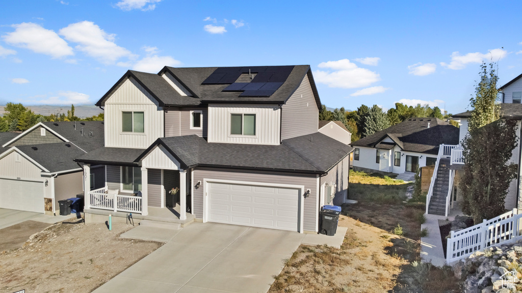 View of front of property featuring a garage, a porch, and solar panels