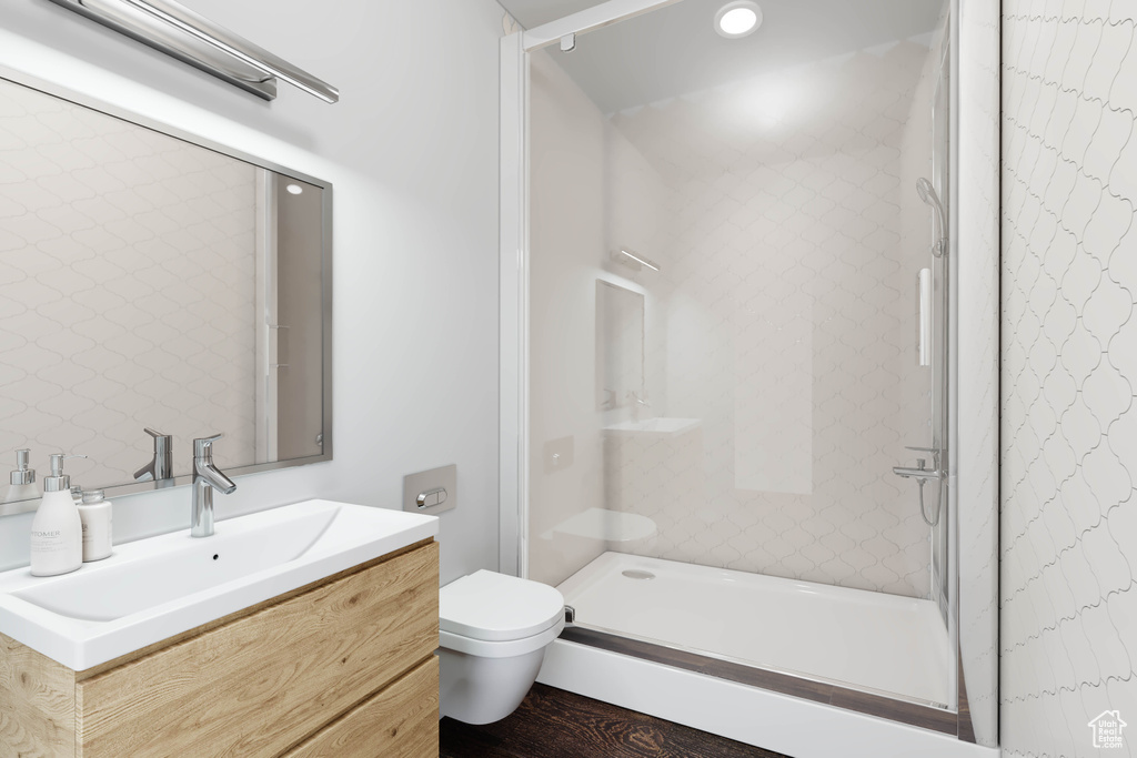 Bathroom with hardwood / wood-style flooring, vanity, toilet, and tiled shower