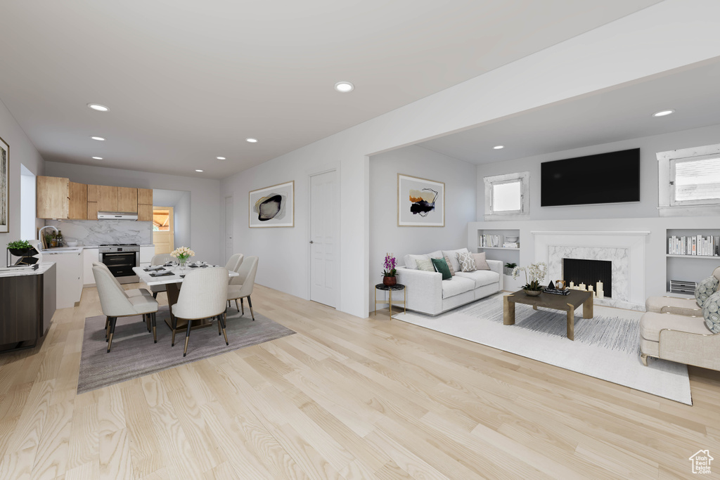 Dining room with a high end fireplace, light hardwood / wood-style flooring, and plenty of natural light